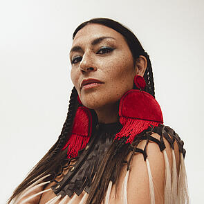 A woman with large red earrings looks into the camera