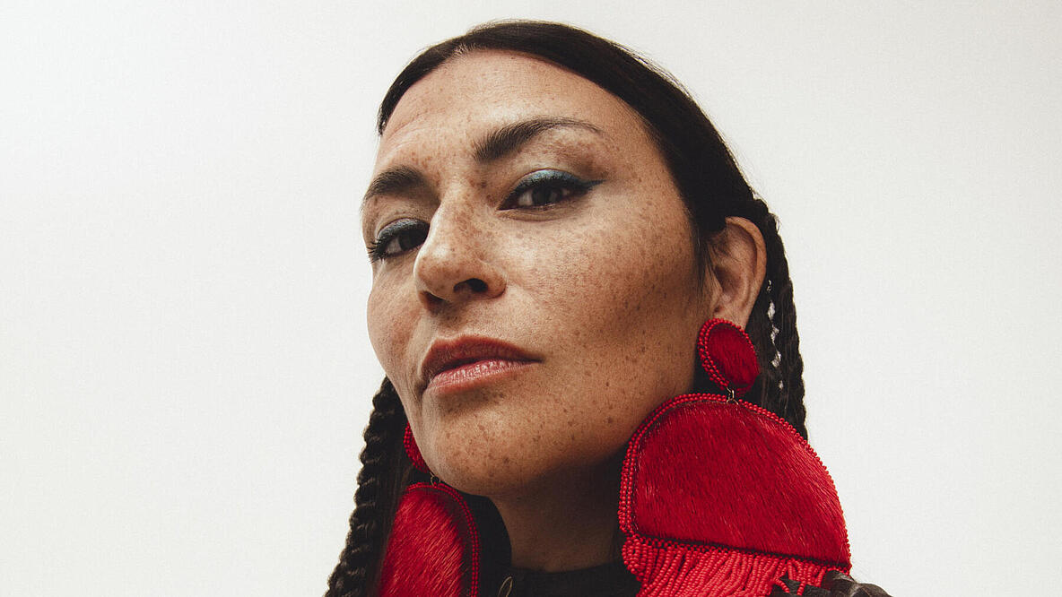A woman with large red earrings looks into the camera