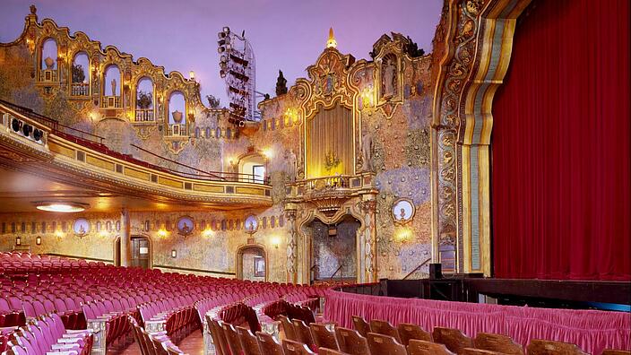 View of a magnificent, golden decorated theater hall with lots of red velvet.