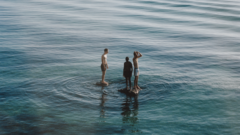 Drei Menschen stehen auf einer Wasserfläche. 