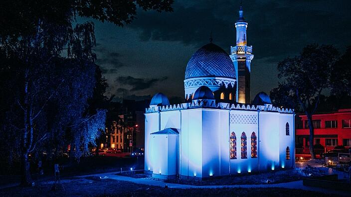 A mosque lit up in blue at night.