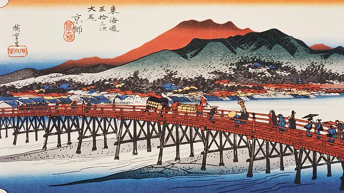 Illustration zeigt eine Holzbrücke über einen Fluss. Etliche Menschen überqueren den Fluss mit Gepäck und Wagen. Im Hintergrund ist eine Stadt aus niedrigen Häusern zu sehen und zwei Berge