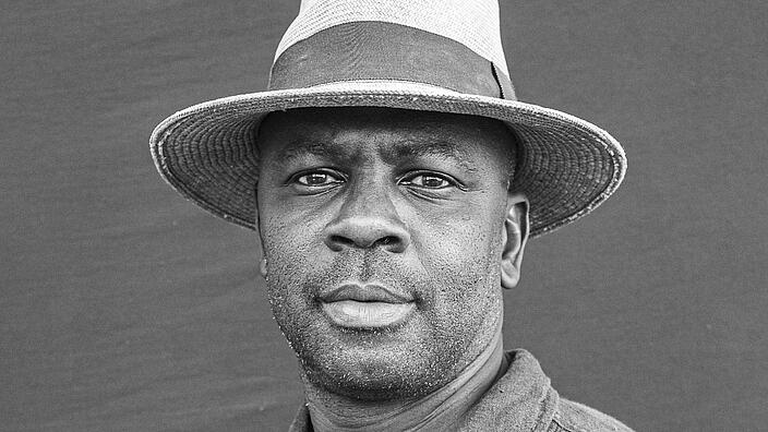 A black and white portrait photo of the author and former professional footballer Lilian Thuram. He wears a hat and looks into the camera.