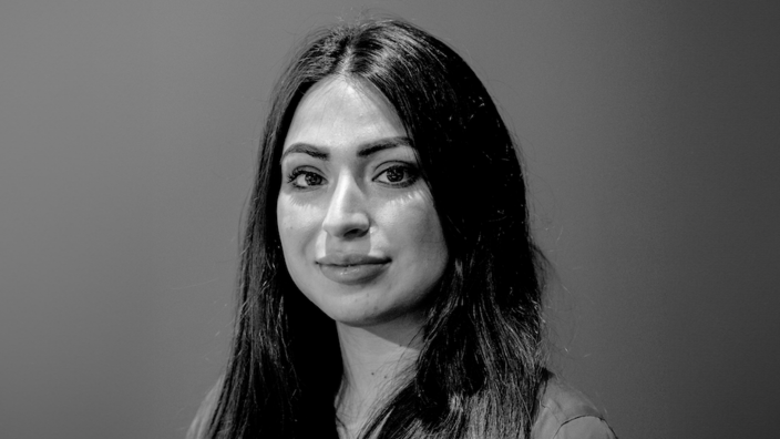 A black and white portrait photo of the author Lale Gül. She wears her long hair open and parted in the middle.