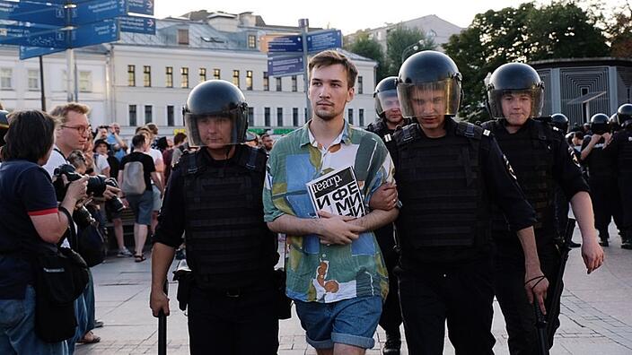 Der Autor Alexander Finiarel wird 2019 nach Protesten auf dem Tsvetnoy Boulevard in Moskau von vier Polizisten mit schusssicheren Westen, Helmen und Schlagstöcken verhaftet und abgeführt.