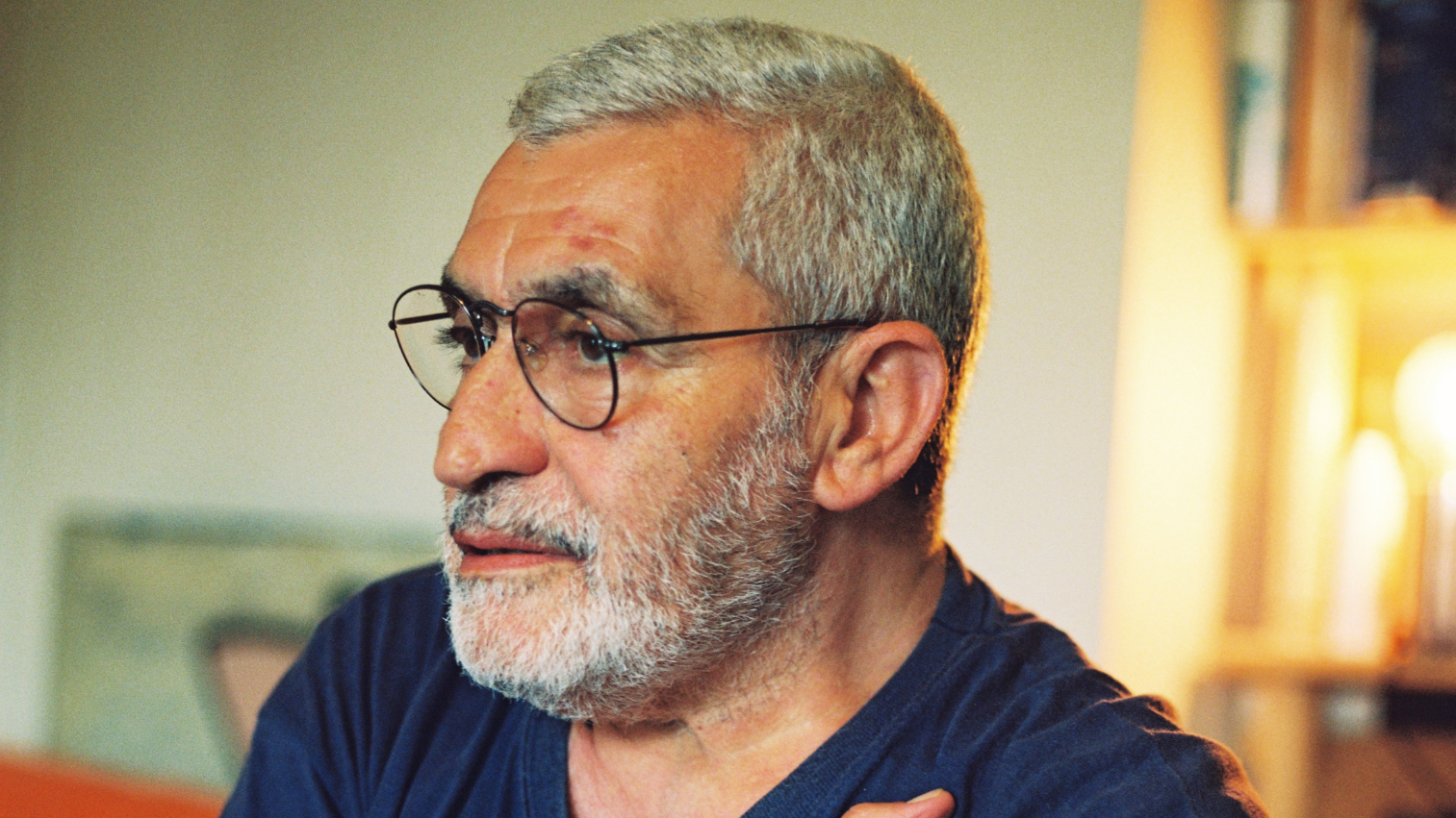 Portrait of an elder man with a grey beard and glasses.