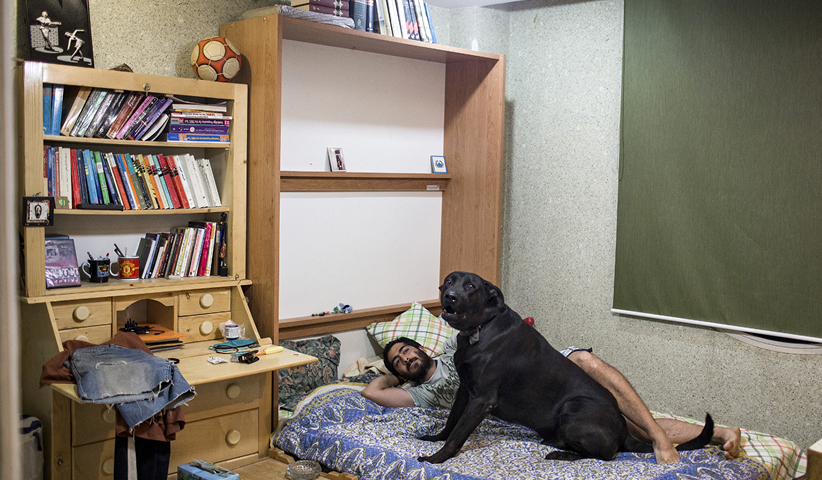 Ein Mann mit seinem Hund im Schlafzimmer. Hunde dürfen in Iran nicht gehalten werden, weil sie im Islam als unrein gelten. Die meisten Hundebesitzer lassen ihre Tiere daher im Haus. Teheran, 2013