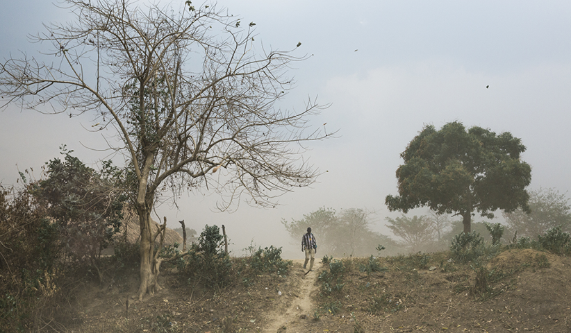 A farmer walks to his field outside the village of Zawara, shortly after a storm has swept over it. Although the village is only 24 kilometres east of the capital Bangui, it is isolated. There are hardly any roads to get there