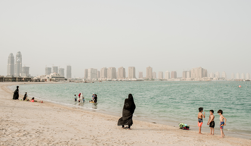 Families refresh themselves from the heat of a beach of Doha