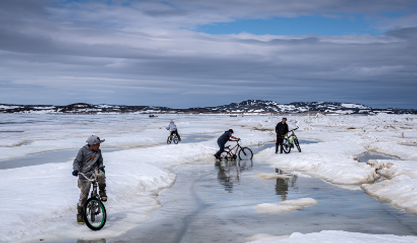 After a long, dark winter, children from the Inuit settlement of Cape Dorset in the state of Nunavut ride their bicycles through the melting snow