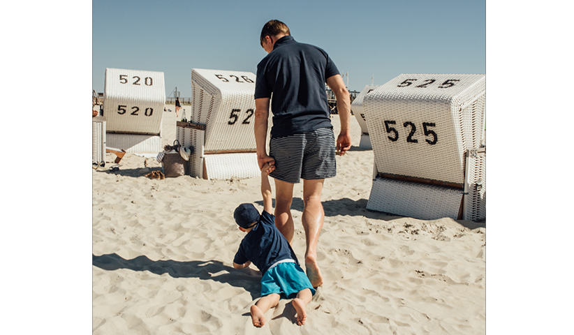 A father drags his son across a sandy beach in St Peter-Ording, 2018