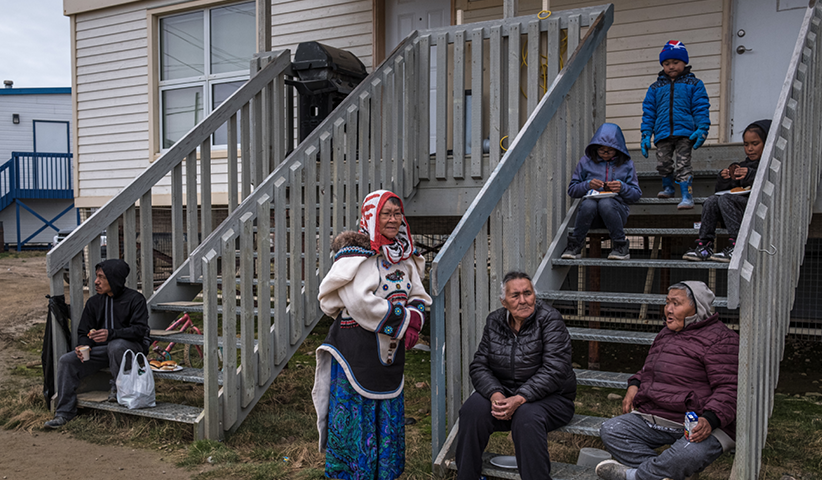 Cape Dorset residents sit outside their homes. Many of them live in social housing.