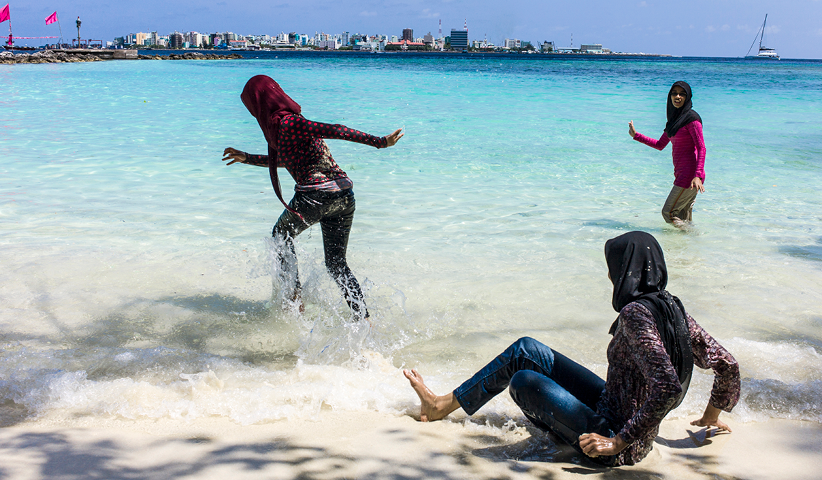 Malediver gehen an der Strandpromenade von Malé schwimmen