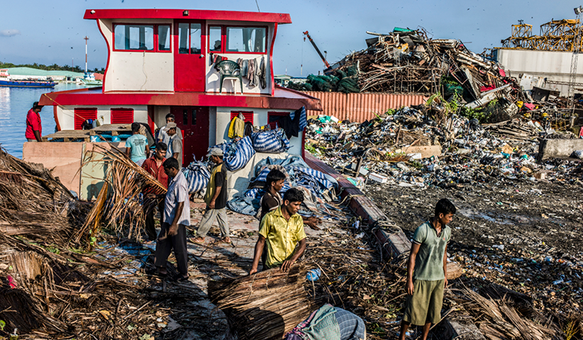 Arbeiter aus Bangladesch entladen und sortieren Müll auf der Insel Thilafushi